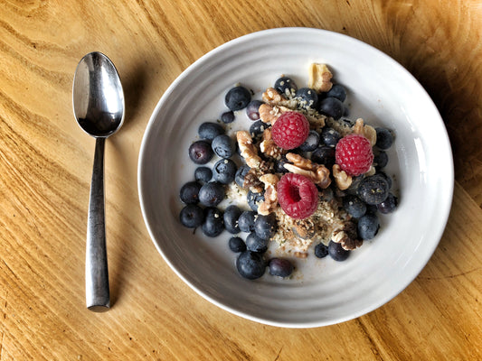 white bowl filled with brown rice and berries on a wood table with a spoon